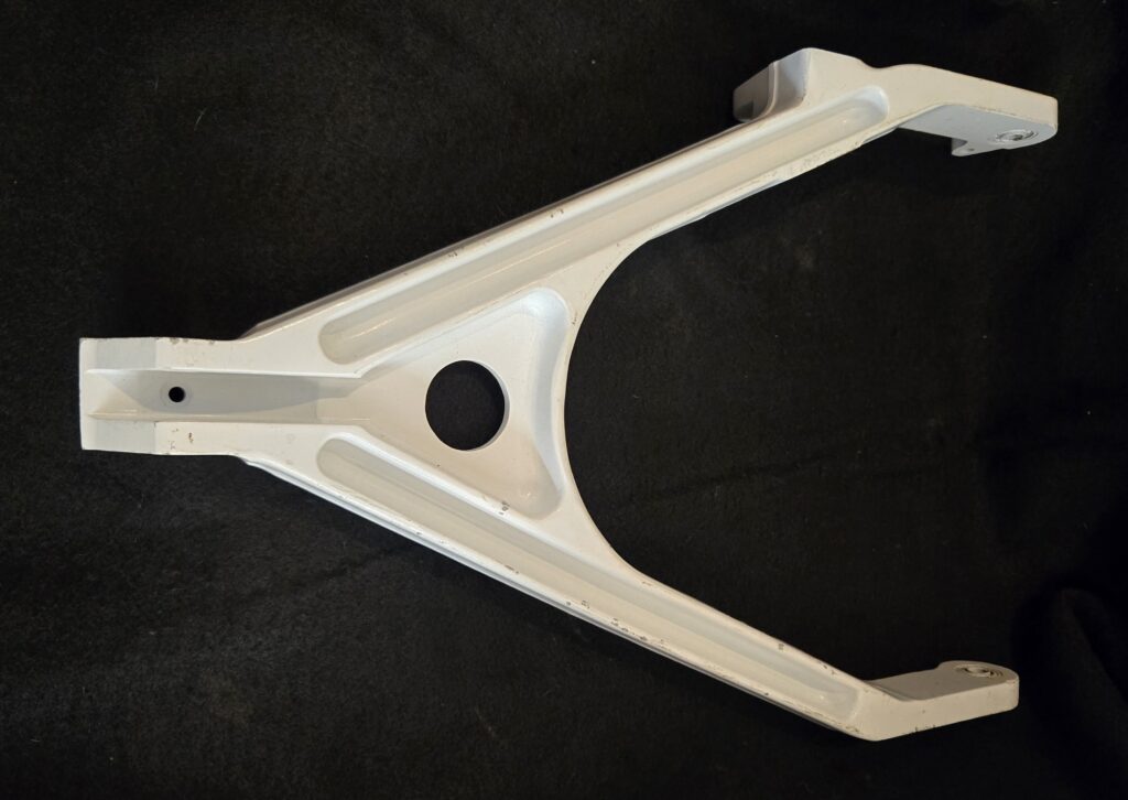 White metal bracket with a curved central channel and circular holes on a black background.