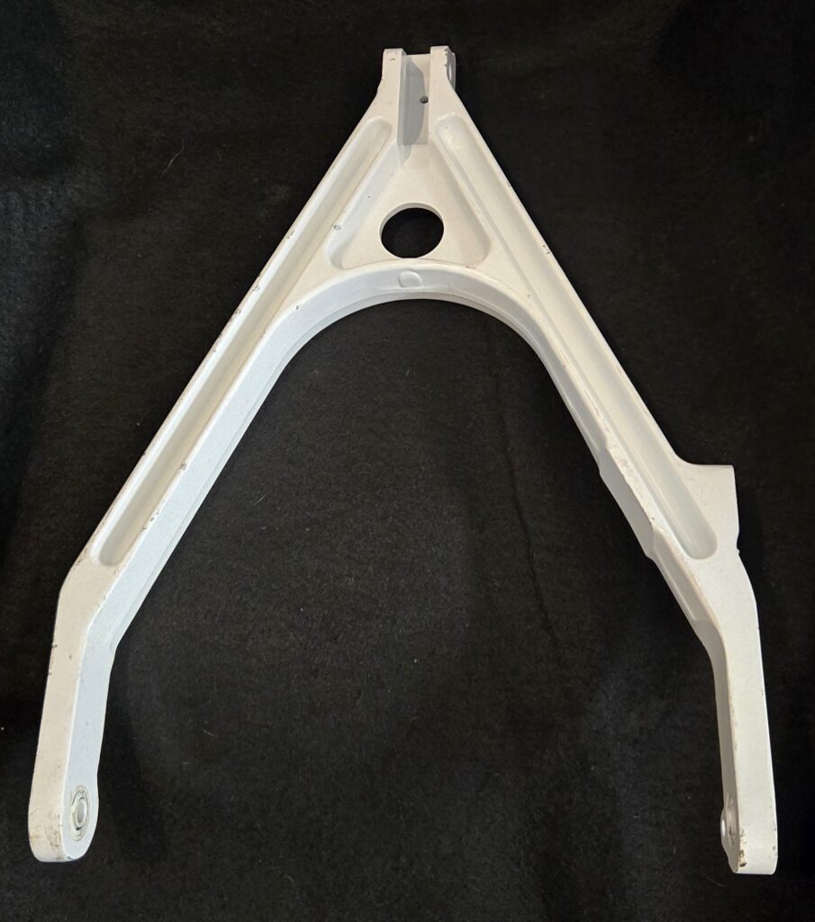 White triangular metal frame with a circular hole near the top, set against a dark background.