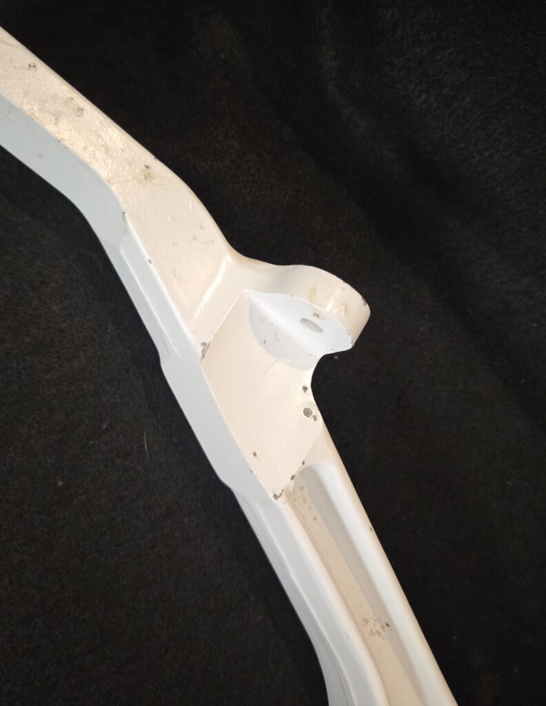 Close-up of a white plastic mounting bracket with dirt specks on a dark fabric background.