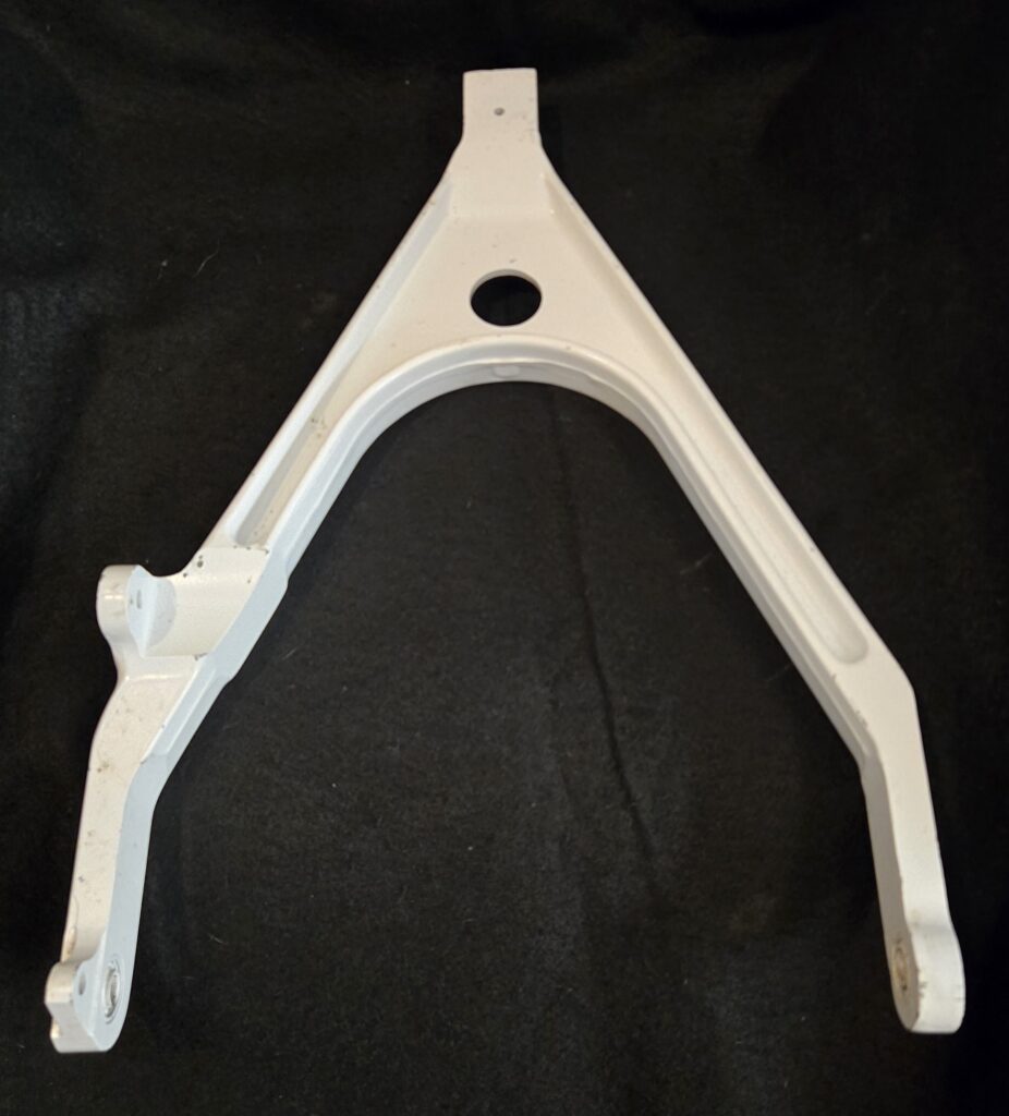 White triangular plastic frame with a central circular hole and a small tab at the top, set against a dark background, likely a mounting bracket.